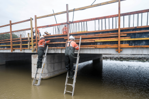 Two workers working around water at Camp Street mid construction